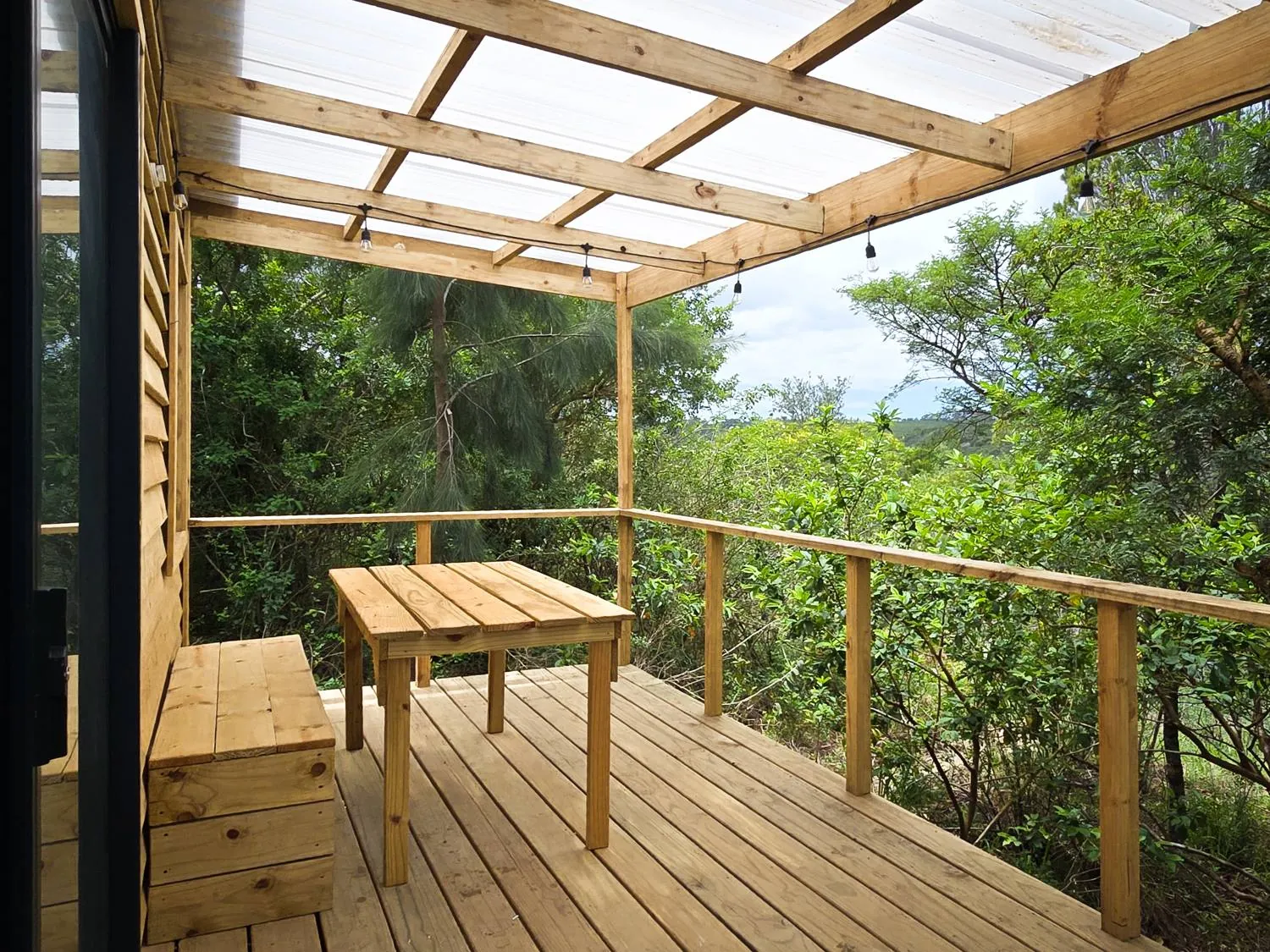 A covered deck with string lights reaching into the treetops